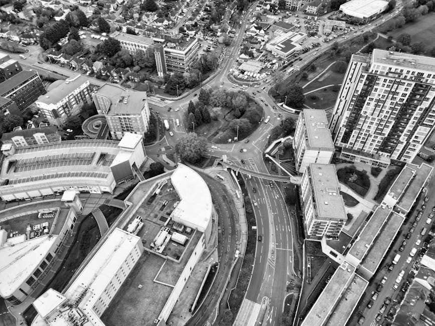This black-and-white aerial photograph captures a busy urban scene in Bracknell town centre, with streets intersecting at a roundabout surrounded by modern high-rise buildings, commercial structures,