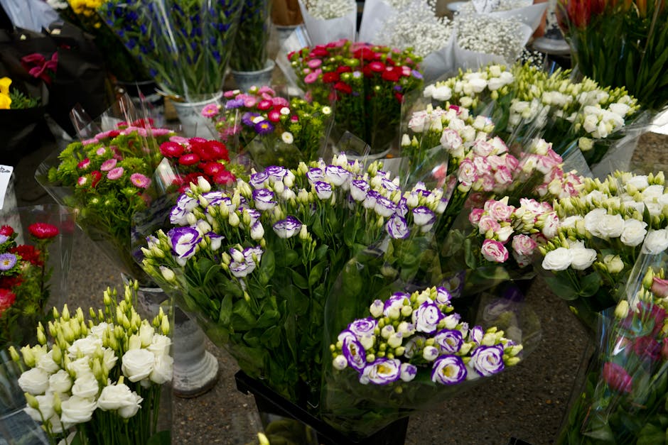 A vibrant display of fresh floral arrangements featuring a variety of flowers including purple and white eustoma (lisianthus), pink and white roses, red and pink daisies, and white lisianthus, all arr